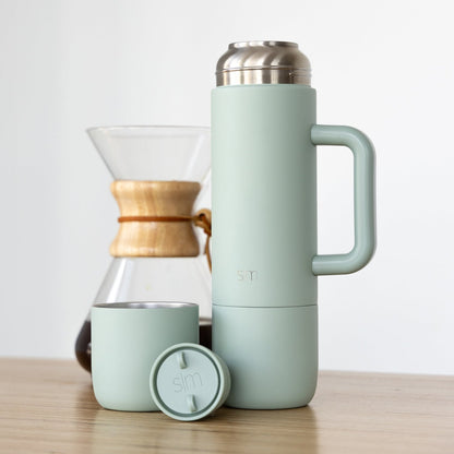 Simple Modern branded products in soft sage green displayed with warm natural wood tones
